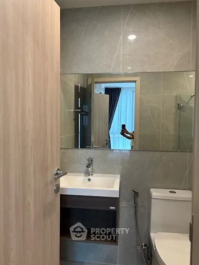 Modern bathroom with sleek sink and large mirror in stylish apartment.