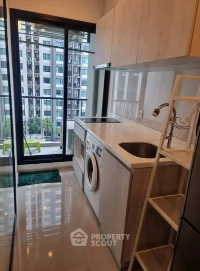 Modern kitchen with balcony view and built-in appliances in urban apartment