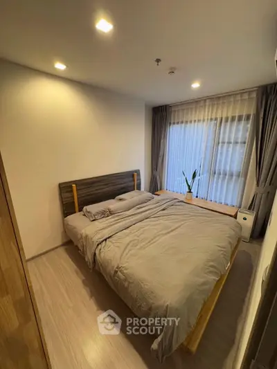 Cozy bedroom with modern decor and large window for natural light.