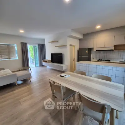 Modern open layout living room and kitchen with stylish furniture and natural light.