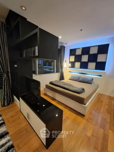 Modern bedroom with stylish decor and wooden flooring, featuring a sleek bed and ambient lighting.