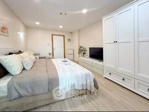 Spacious modern bedroom with stylish decor and ample storage in a cozy apartment.