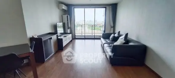 Spacious living room with modern furniture and large window offering city view.