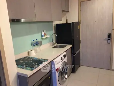 Compact modern kitchen with washing machine and sleek cabinetry in urban apartment.