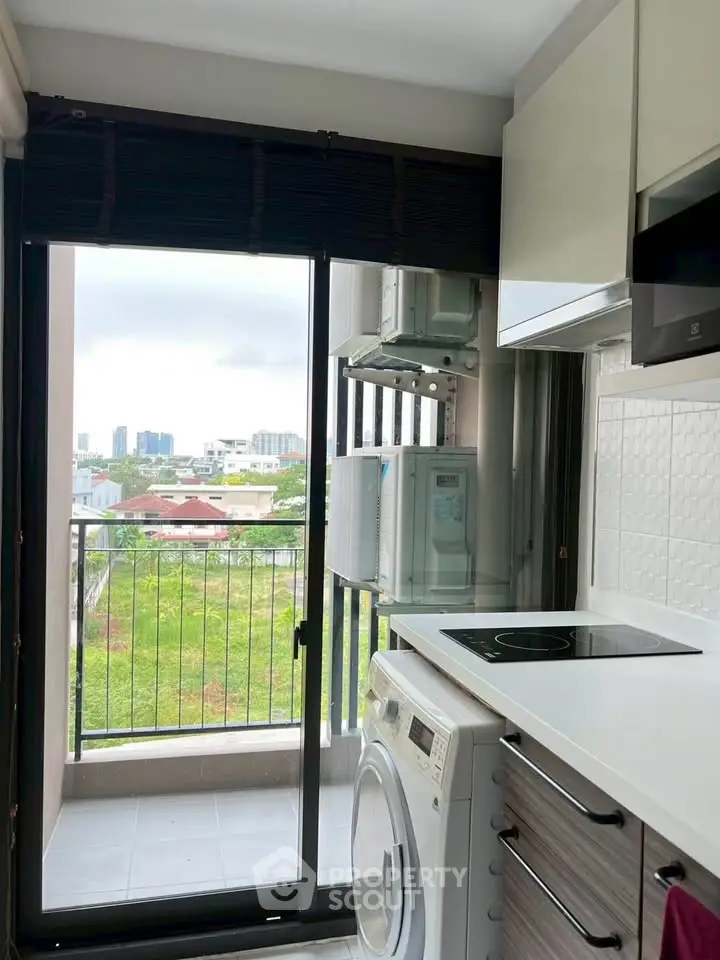 Modern kitchen with balcony view, featuring sleek appliances and ample natural light.