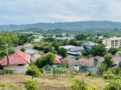 Scenic view of residential area with lush greenery and mountains in the background.