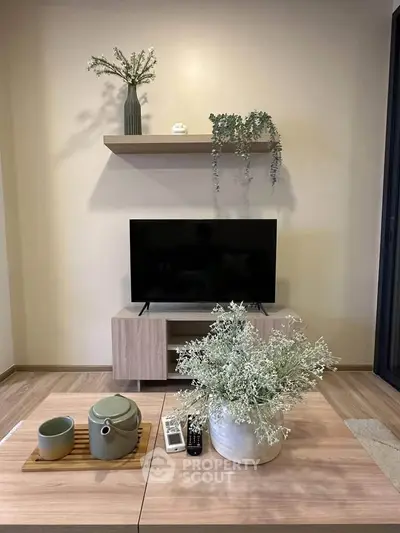 Modern living room with stylish decor and flat-screen TV on wooden stand.