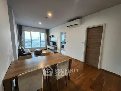 Spacious living room with wooden flooring and city view, featuring modern furniture and air conditioning.