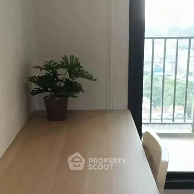 Modern study area with wooden desk and potted plant near balcony view.