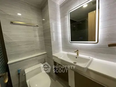 Modern bathroom with sleek fixtures and illuminated mirror in a stylish real estate property.