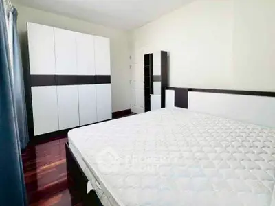 Spacious bedroom with modern furniture and ample natural light.