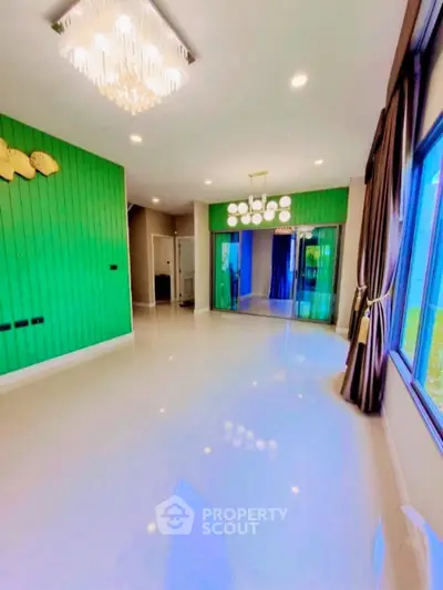 Spacious modern living room with vibrant green accent wall and elegant lighting fixtures.