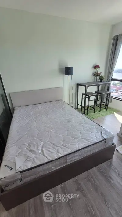 Modern bedroom with large window and stylish furniture in a high-rise apartment.