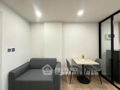 Modern living room with sleek gray sofa and dining area in minimalist apartment.