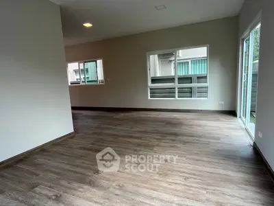 Spacious empty living room with wooden flooring and large windows