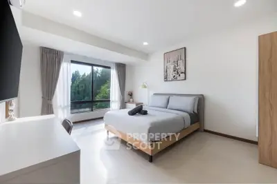 Modern bedroom with large window and stylish decor in a bright apartment.