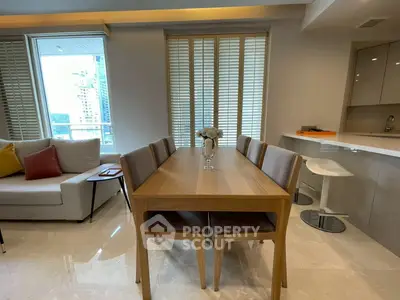 Modern dining area with sleek wooden table and chairs, adjacent to a stylish kitchen and cozy living space.