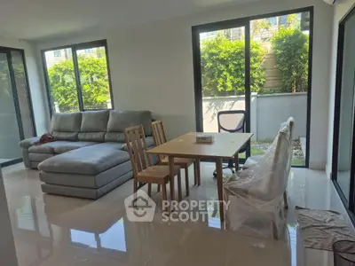Spacious living room with modern furniture and large windows overlooking greenery.