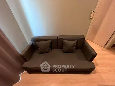 Cozy living room with modern dark sofa and wooden flooring, perfect for relaxation.