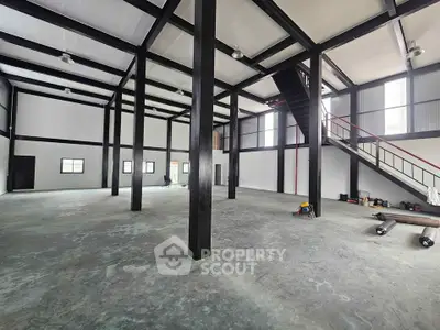 Spacious industrial-style interior with high ceilings and mezzanine level, ideal for versatile commercial use.