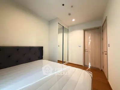 Modern bedroom with mirrored closet and wooden flooring