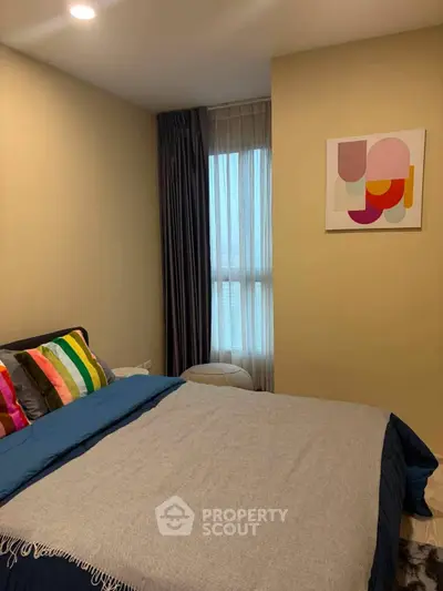 Cozy bedroom with colorful pillows and modern art, perfect for relaxation.