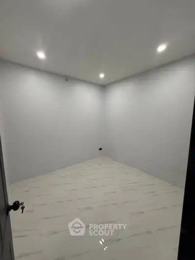 Spacious empty room with modern lighting and tiled flooring, perfect for customization.