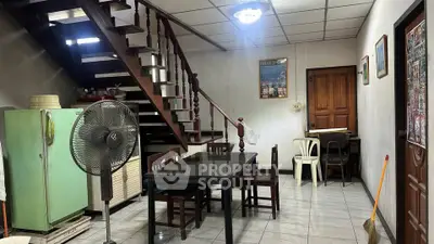 Charming interior with vintage staircase and dining area, featuring retro fridge and cozy ambiance.