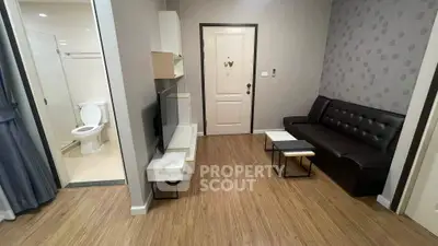 Modern living room with sleek furniture and adjacent bathroom, showcasing stylish interior design.