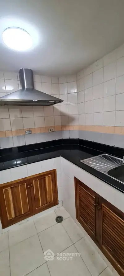Cozy kitchen with sleek black countertops and wooden cabinets, perfect for culinary enthusiasts.