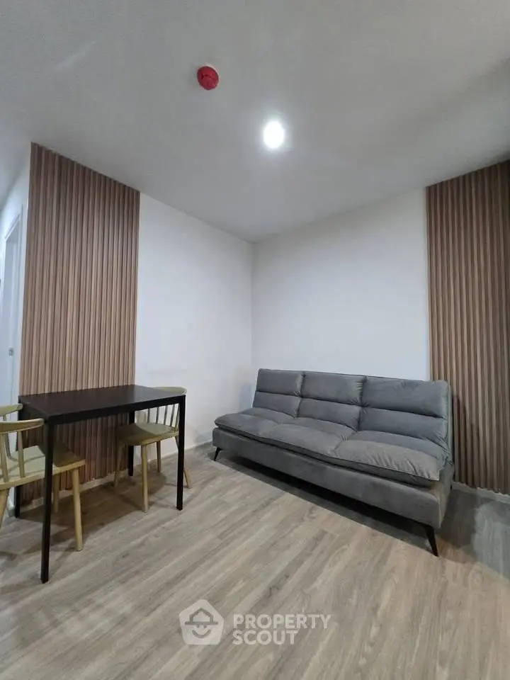 Modern living room with stylish sofa and dining area, featuring elegant wood paneling and contemporary lighting.