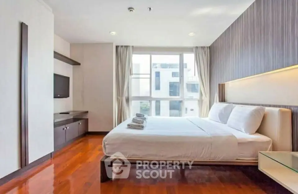 Spacious modern bedroom with large window and elegant wooden flooring