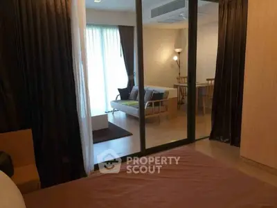 Spacious bedroom with sliding glass doors leading to a cozy living area, featuring modern furniture and soft lighting.