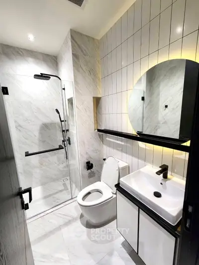 Modern bathroom with sleek design, featuring a glass shower enclosure and stylish fixtures.