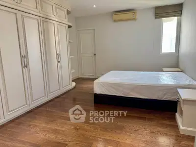 Spacious bedroom with wooden flooring and built-in wardrobe, perfect for modern living.