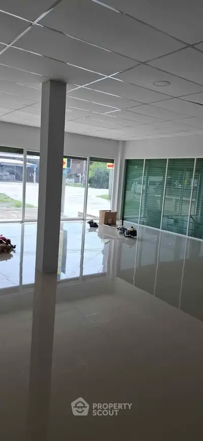 Spacious commercial space with large windows and glossy floors ideal for business setup.