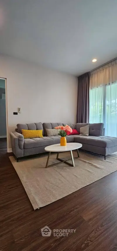 Modern living room with stylish gray sectional sofa and vibrant cushions, complemented by a chic round coffee table.