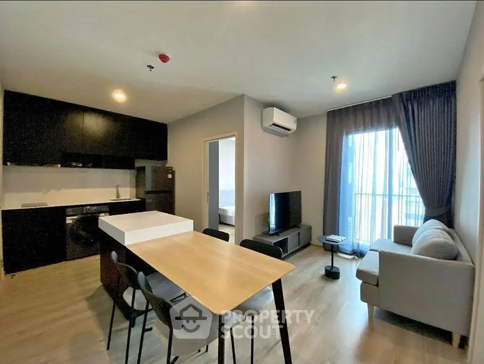 Modern open-plan living room with kitchen, dining area, and balcony access in a stylish apartment.