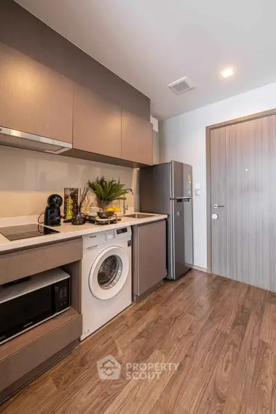 Modern kitchen with sleek appliances and wood flooring in a stylish apartment.