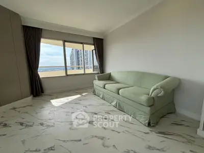 Spacious living room with elegant marble flooring and a cozy green sofa, featuring large windows with city views.