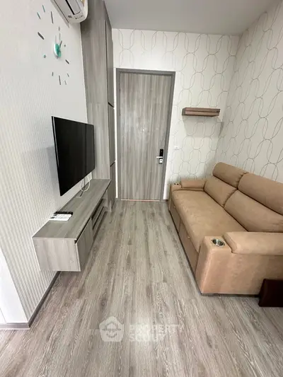 Modern living room with sleek design and cozy sofa, featuring wall-mounted TV and stylish flooring.