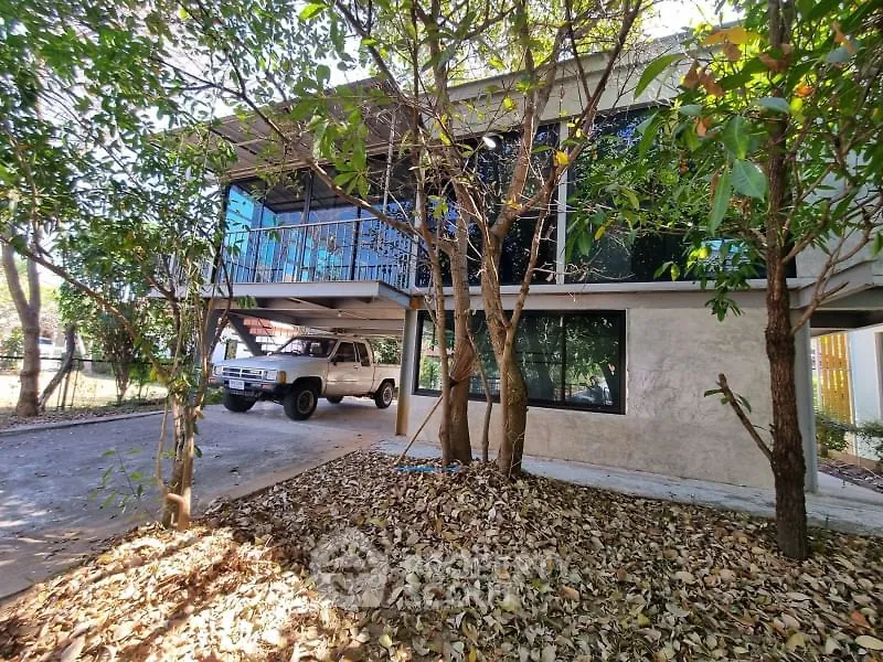 Charming two-story home with carport surrounded by lush trees and natural landscaping.