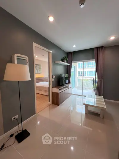 Modern living room with sleek design and natural light, featuring a view of the bedroom and balcony.