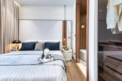 Luxurious bedroom with modern decor and ensuite bathroom, featuring elegant lighting and cozy bedding.