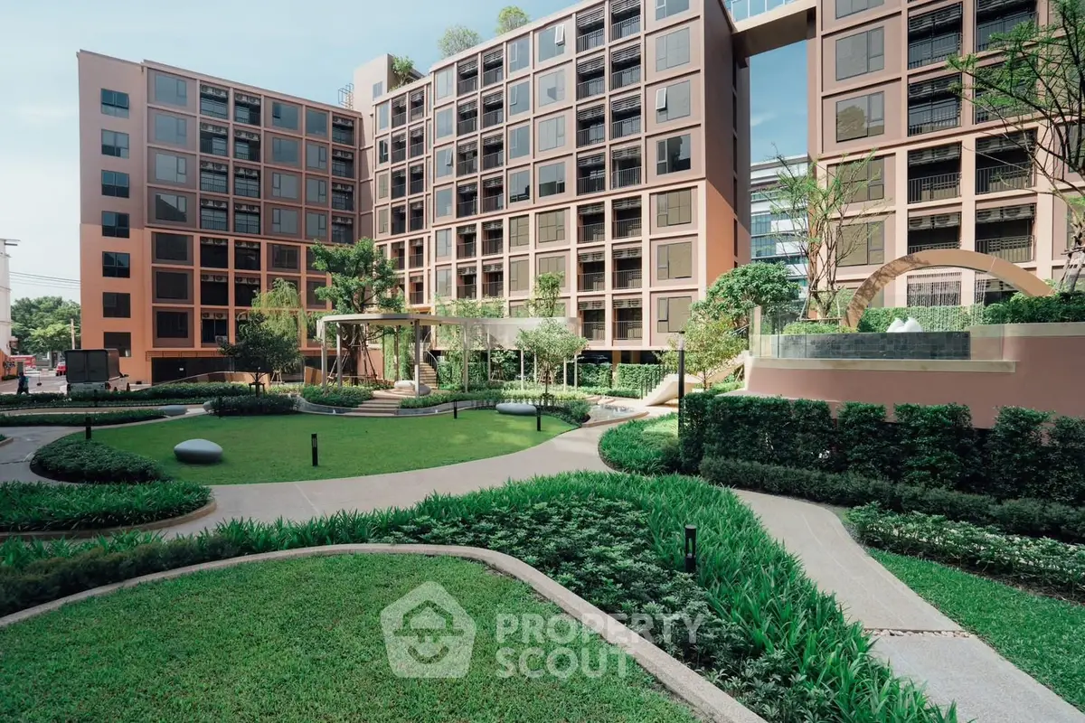 Modern apartment building with lush landscaped garden and pathways, offering serene urban living.