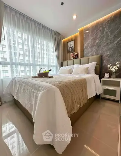 Luxurious bedroom with modern decor and large window view in high-rise apartment.
