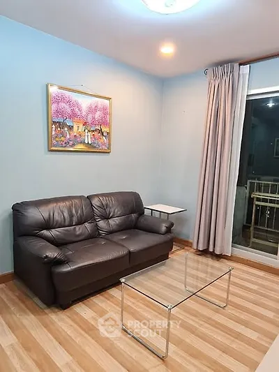 Cozy living room with leather sofa and glass coffee table, perfect for relaxation.