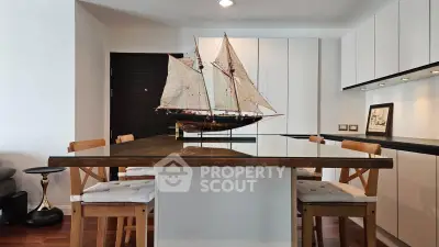 Modern kitchen with sleek cabinetry and elegant dining area featuring a unique ship model centerpiece.