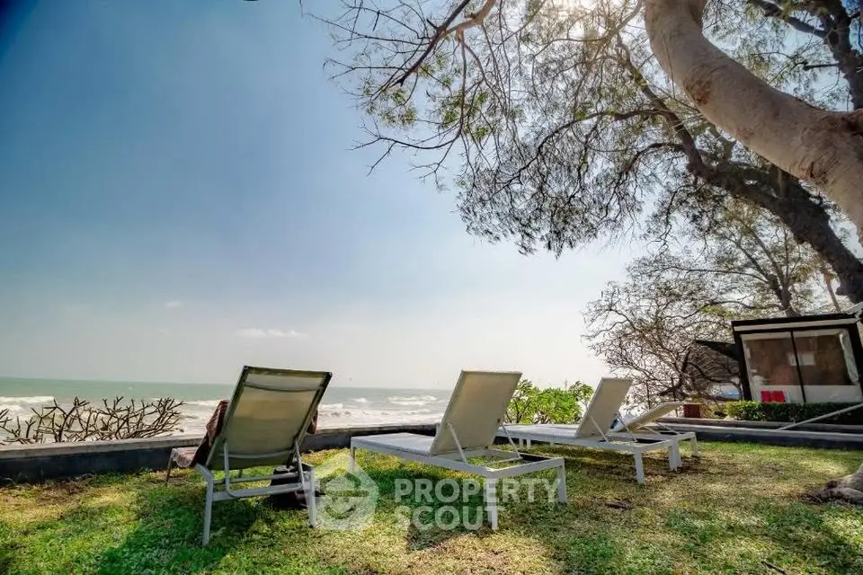 Beachfront property with lounge chairs and ocean view, perfect for relaxation.