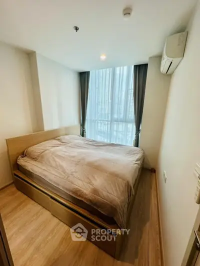 Cozy bedroom with large windows allowing ample natural light, complete with a comfortable bed and air conditioning for a restful ambiance.